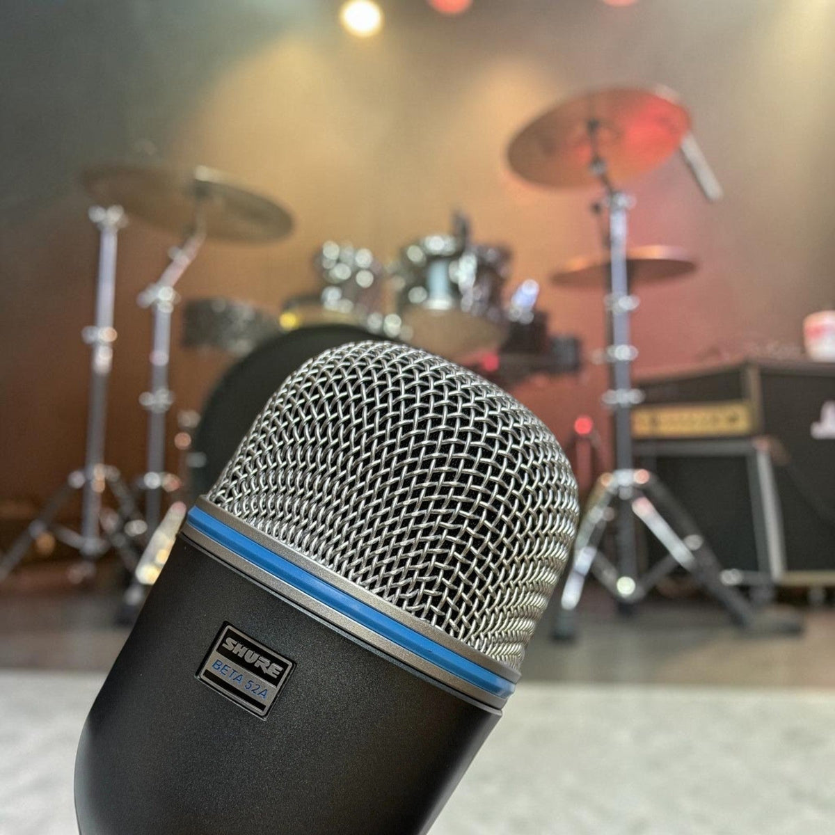 Shure Beta 52A kick drum microphone in front of a drum kit on a club stage