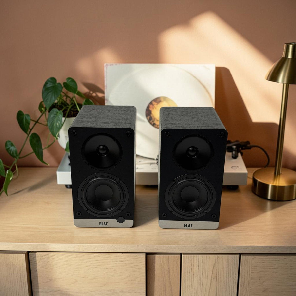 ELAC Debut ConneX powered bookshelf speakers on a media console in a warm, modern living room.